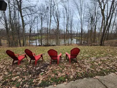 a group of four red chairs sitting in a park at Eagles Nest At Heron Hill Retreat Hot Tub on Lake! in Streetsboro