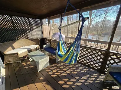 a porch with a hammock and a table and chairs at Eagles Nest At Heron Hill Retreat Hot Tub on Lake! in Streetsboro