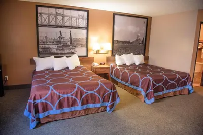 a hotel room with two beds and pictures on the wall at Super 8 by Wyndham Gallipolis Pt Pleasant Area in Gallipolis