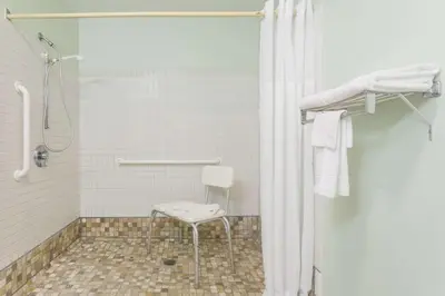 a shower with a chair in a bathroom at Super 8 by Wyndham Gallipolis Pt Pleasant Area in Gallipolis