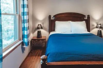 a bedroom with a bed with blue sheets and a window at King Bed House w Private Hot Tub in South Bloomingville