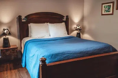 a bedroom with a bed with a blue blanket and two lamps at King Bed House w Private Hot Tub in South Bloomingville