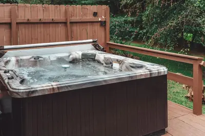 a hot tub on a patio next to a fence at King Bed House w Private Hot Tub in South Bloomingville