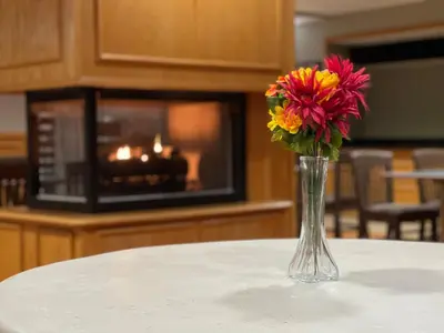 a vase of flowers sitting on a table with a microwave at FairBridge Inn & Suites Fort Wayne in Fort Wayne