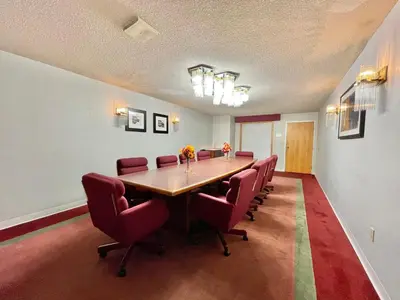 a conference room with a long table and red chairs at FairBridge Inn & Suites Fort Wayne in Fort Wayne