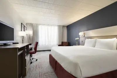 a hotel room with a large bed and a flat screen tv at Ramada by Wyndham Beaver Falls in Beaver Falls