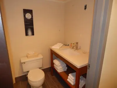 a bathroom with a toilet and a sink and a clock at Ramada by Wyndham Beaver Falls in Beaver Falls