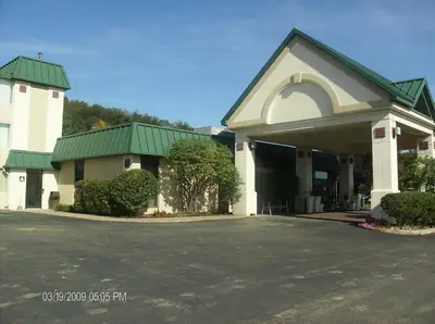a building with a green roof and a parking lot at Ramada by Wyndham Beaver Falls in Beaver Falls