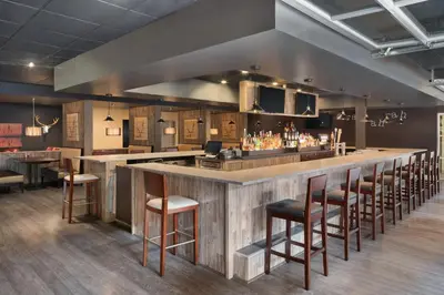 a bar in a restaurant with bar stools at Ramada by Wyndham Beaver Falls in Beaver Falls