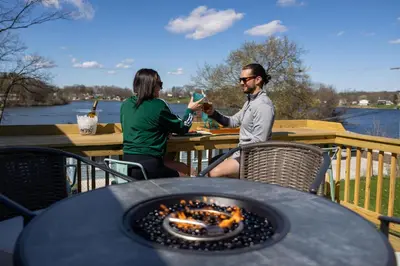 a man and woman sitting at a table with a fireplace at Hilltop Lakehouse - Free Kayaks Deck PLX in Akron