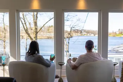 two people sitting in chairs looking out the window at Hilltop Lakehouse - Free Kayaks Deck PLX in Akron