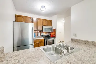 a kitchen with a sink and a stainless steel refrigerator at Lakefront Port Clinton Condo with Boat Dock and Slip! in Port Clinton