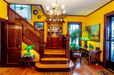 a yellow room with a staircase and a chandelier at Mike & Allen's Place on the Park_1 in Columbus