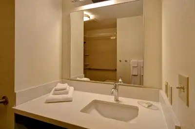 a bathroom with a sink and a large mirror at Candlewood Suites Carrollton by IHG in Carrollton