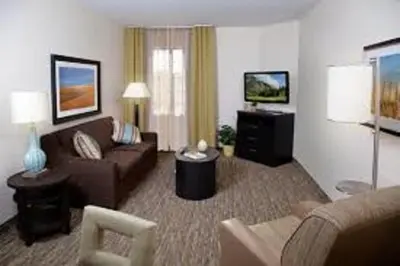 a living room with a couch and a tv in a hotel room at Candlewood Suites Carrollton by IHG in Carrollton