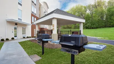 two bbq grill and television in front of a building at Candlewood Suites Carrollton by IHG in Carrollton