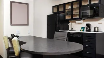 a kitchen with a table and a black counter top at Candlewood Suites Carrollton by IHG in Carrollton