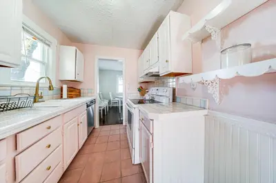 a kitchen with white cabinets and a tile floor at Coastal Lake Erie Cottage with Amazing Water Views! in Euclid