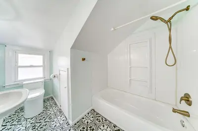 a white bathroom with a tub and a sink at Coastal Lake Erie Cottage with Amazing Water Views! in Euclid