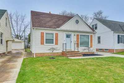 a white house with an orange door and a yard at The Maple Tree Home 14 Mi to Downtown Cleveland in Maple Heights