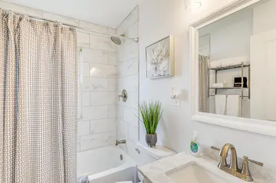 a white bathroom with a sink and a tub at The Maple Tree Home 14 Mi to Downtown Cleveland in Maple Heights