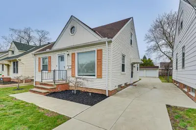 a white house with a porch and a driveway at The Maple Tree Home 14 Mi to Downtown Cleveland in Maple Heights