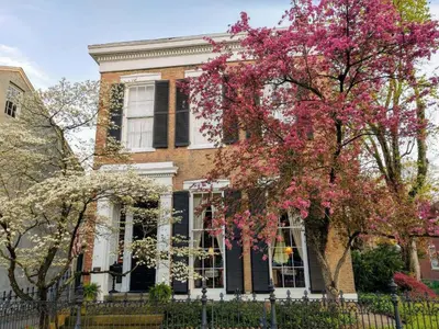 a brick house with pink flowering trees in front of it at Iron Gate Inn in Madison