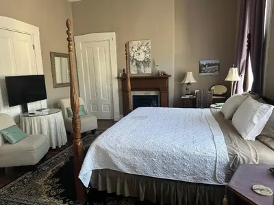 a bedroom with a bed and a chair and a fireplace at Iron Gate Inn in Madison