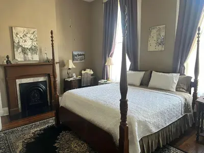 a bedroom with a canopy bed and a fireplace at Iron Gate Inn in Madison