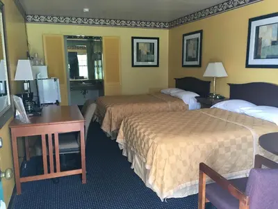 a hotel room with two beds and a desk at Norwalk Inn in Norwalk