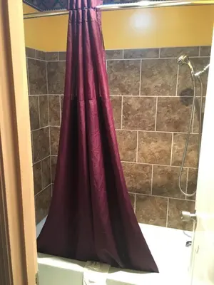 a bathroom with a shower with a red shower curtain at Norwalk Inn in Norwalk