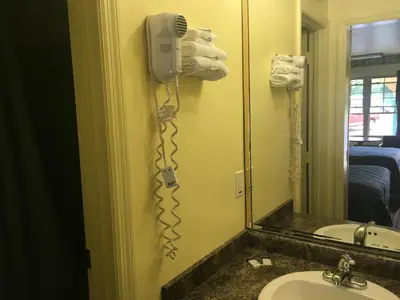 a bathroom with a phone on the wall next to a sink at Norwalk Inn in Norwalk