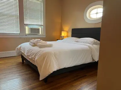 a bedroom with a bed with white sheets and a window at Stay with Jay - Quinta Suite in Cleveland