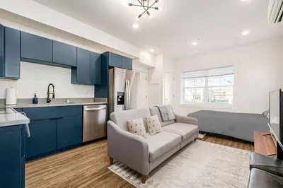 a kitchen with blue cabinets and a couch in a room at Central Loft with Pool Table! Pet-friendly Haven! in Columbus