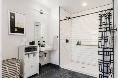 a white bathroom with a shower and a sink at Central Loft with Pool Table! Pet-friendly Haven! in Columbus