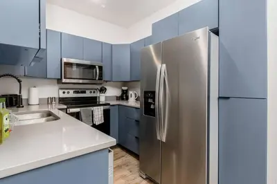 a stainless steel refrigerator in a kitchen with blue cabinets at Designer 1-Bed Haven near Downtown! Pets Welcome! in Columbus