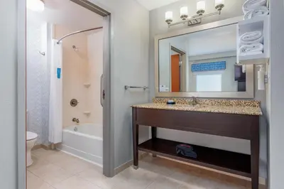 a bathroom with a sink and a tub and a mirror at Hampton Inn and Suites Parkersburg Downtown in Parkersburg