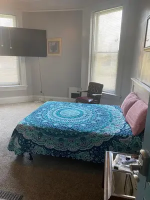 a bedroom with a bed and a chair and windows at Walnut Hills Studio/ Private room in Cincinnati
