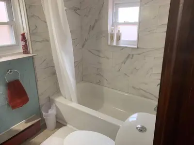a bathroom with a tub and a toilet and a sink at Restored historic log cabin & deck on Lake Erie in Luna Pier