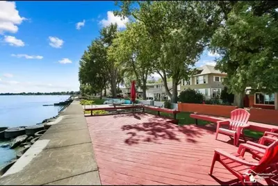 a wooden deck with benches next to a body of water at Restored historic log cabin & deck on Lake Erie in Luna Pier