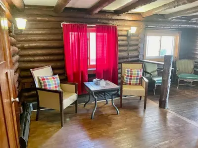 a room with chairs and a table and a red curtain at Restored historic log cabin & deck on Lake Erie in Luna Pier