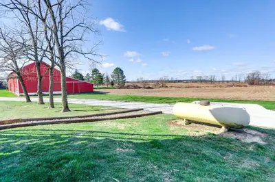 a boat sitting in the grass next to a red barn at Greenwich Countryside Apartment with Shared Yard in Greenwich