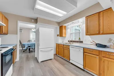 a kitchen with wooden cabinets and a white refrigerator at Central Falls Hideaway in Cuyahoga Falls