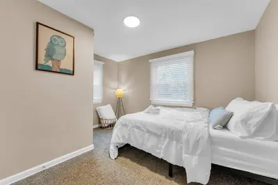 a white bedroom with a bed and a window at Central Falls Hideaway in Cuyahoga Falls