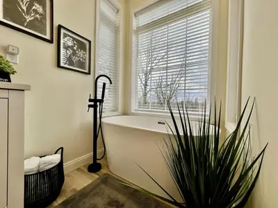 a bathroom with a bath tub and a window at Beautiful NEW Ranch Home with a large deck and games in Maud