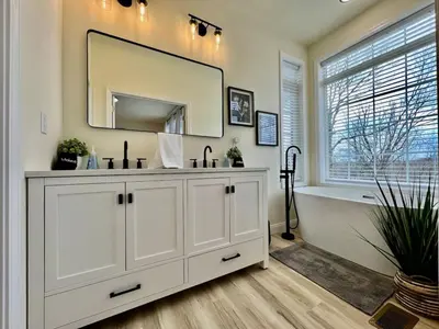 a bathroom with a white vanity and a tub and a mirror at Beautiful NEW Ranch Home with a large deck and games in Maud