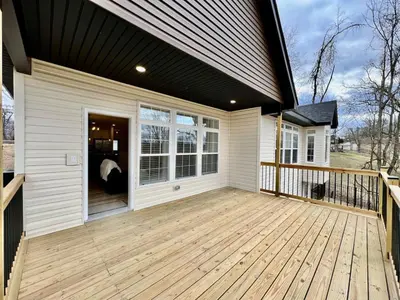 a house with a large porch with a wooden deck at Beautiful NEW Ranch Home with a large deck and games in Maud
