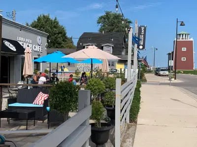 a restaurant with tables and umbrellas on a street at Part of Mini-Mansion, private, 3 story Lake Erie views in Luna Pier