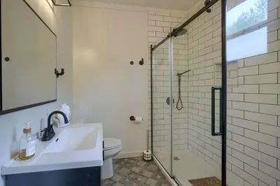 a bathroom with a sink and a glass shower at Swaying Pines Cabin w/EV Charger in South Bloomingville