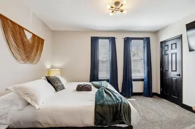 a bedroom with a large white bed with blue curtains at Fairfax Urban Oasis - New Reno - 5 mins to Clinic in Cleveland